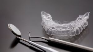 Apparecchio dentale appoggiato su una superficie di fianco a strumenti utili a una pulizia dentale