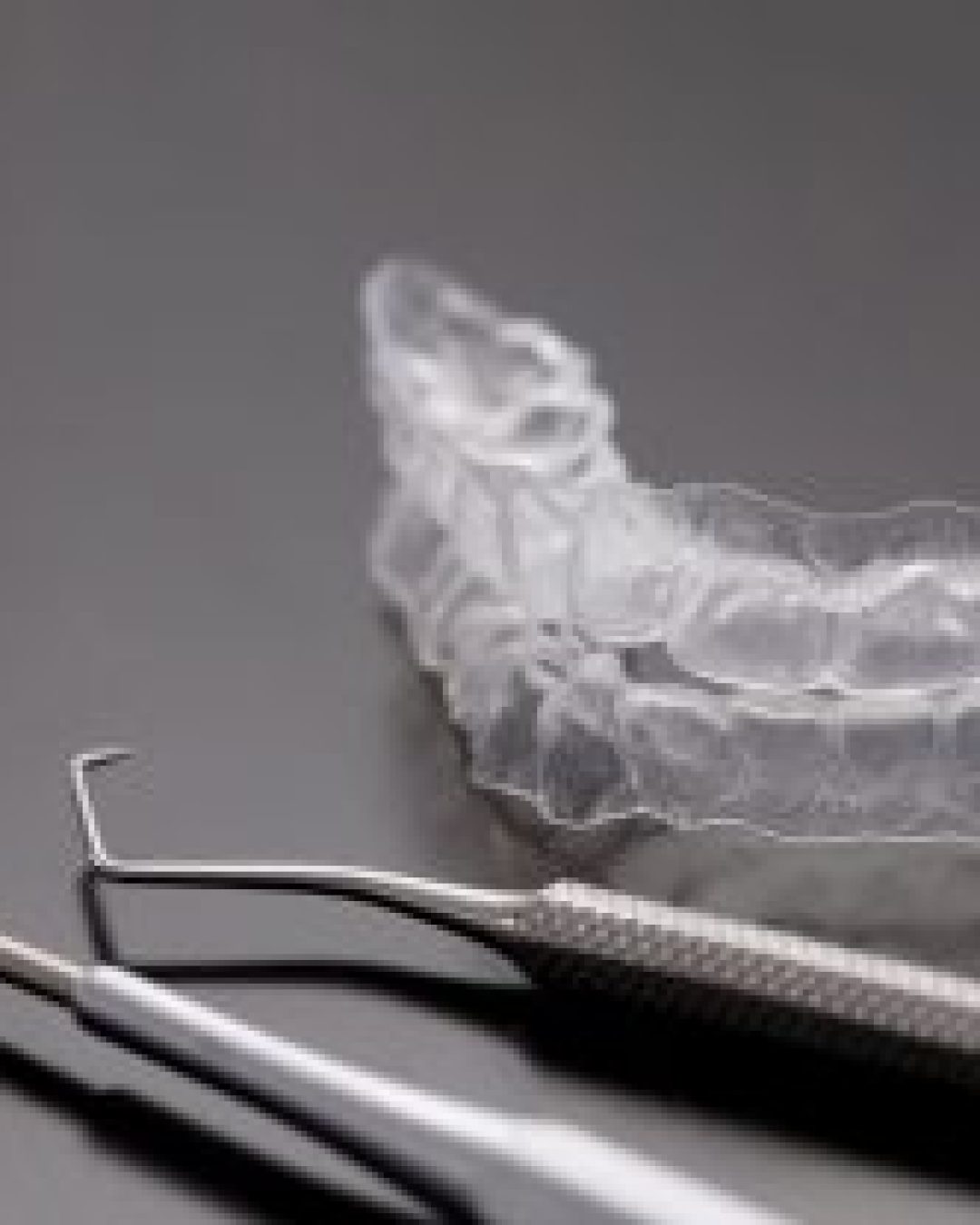 Apparecchio dentale appoggiato su una superficie di fianco a strumenti utili a una pulizia dentale