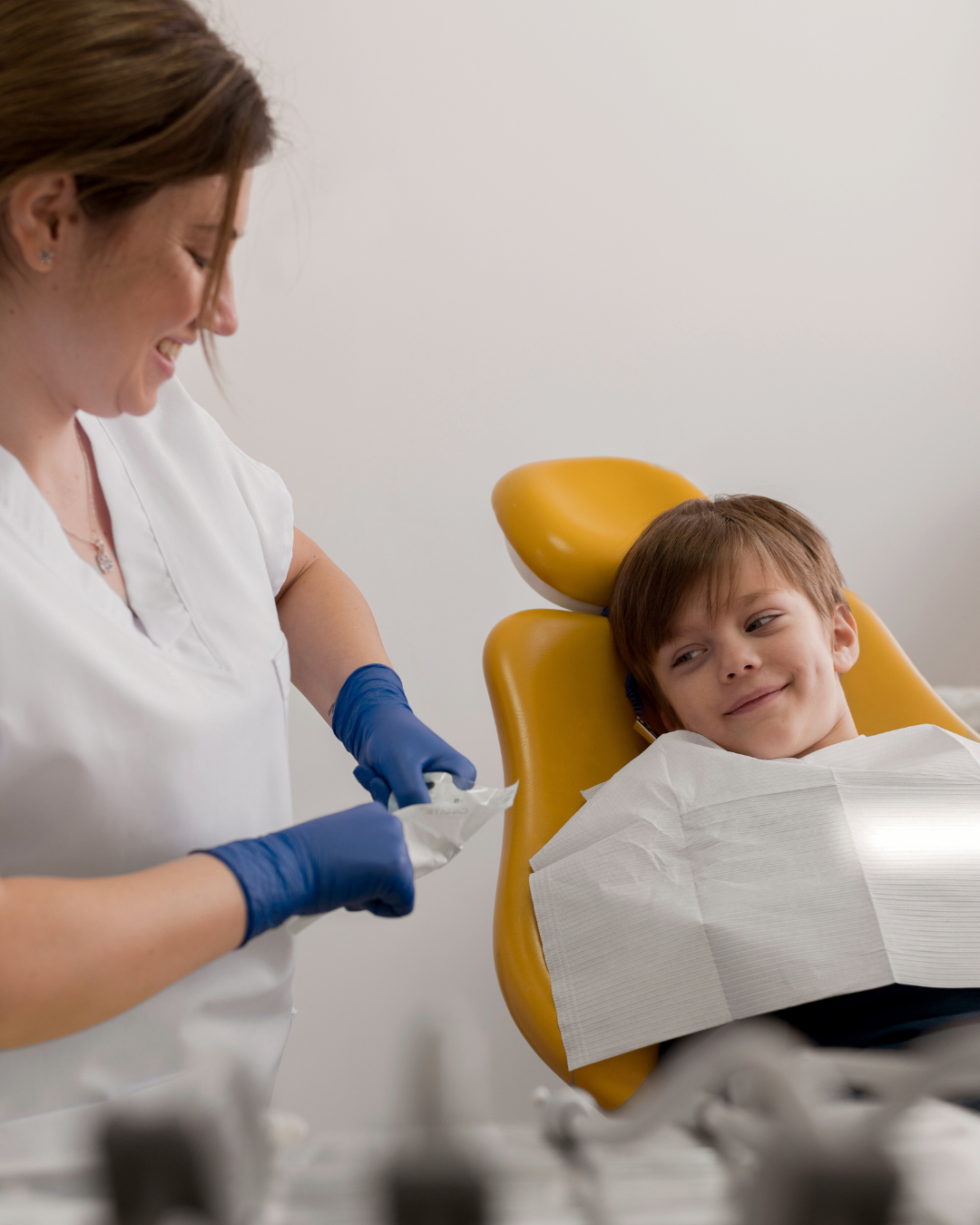 foto di un bambino sorridente seduto su una sedia odontoiatrica durante una visita dentistica