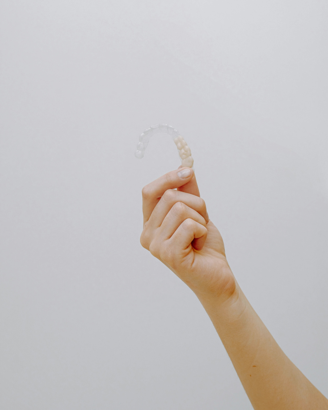 foto su sfondo bianco di una mano che mostra l'invisalign